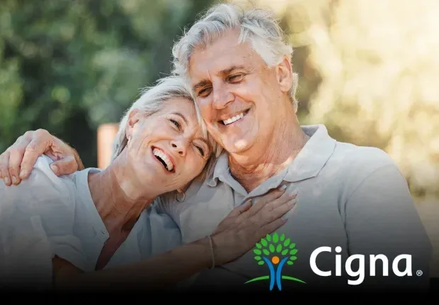 Smiling older couple embracing outdoors, with the Cigna logo displayed.