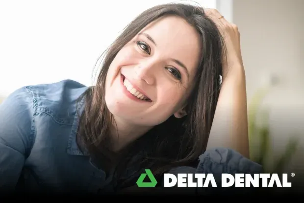 Smiling woman with dark hair resting hand on head, Delta Dental logo below.