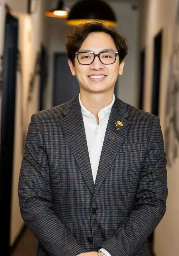 Dr. Matthew Le, Fort Worth dentist, smiling in a plaid blazer in the Flossophy Dental Studio hallway.